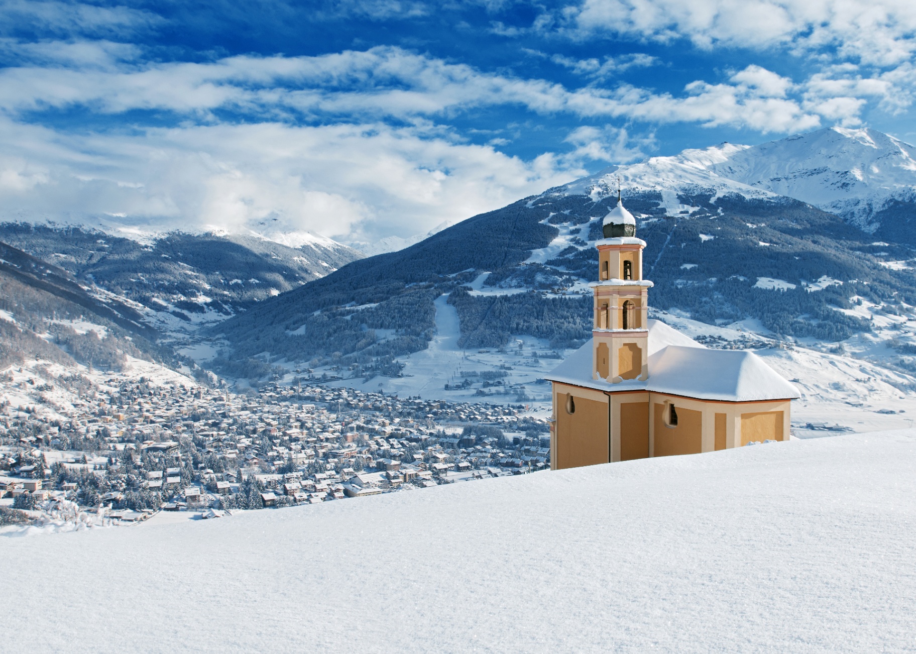 Panorama invernale di Bormio con la chiesa e le montagne innevate